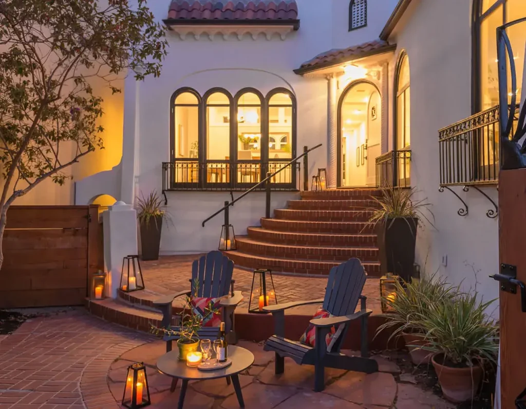 Outdoor table and chairs arranged in front of a stunning staircase, illuminated by ambient lighting for a charming and atmospheric setting